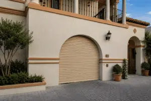 Beige roll-up garage door shutters on a stucco building with arched entryway.